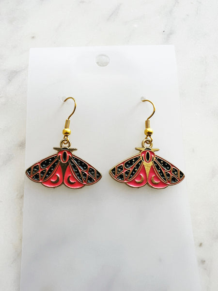Kawaii Moth earrings on a white card with a white marble background