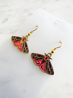 Kawaii Moth earrings on a white card with a white marble background