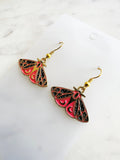 Kawaii Moth earrings on a white card with a white marble background