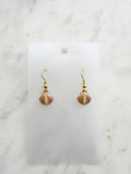Kawai Shell-shaped earrings on a white card with a marble background
