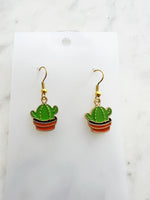 Kawaii Cactus-shaped earrings on a white card with a marble background