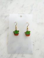 Kawaii Cactus-shaped earrings on a white card with a marble background