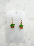 Kawaii Cactus-shaped earrings on a white card with a marble background