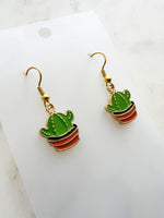 Kawaii Cactus-shaped earrings on a white card with a marble background