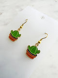 Kawaii Cactus-shaped earrings on a white card with a marble background