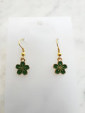 Green flower-shaped earrings on a white card with a marble background