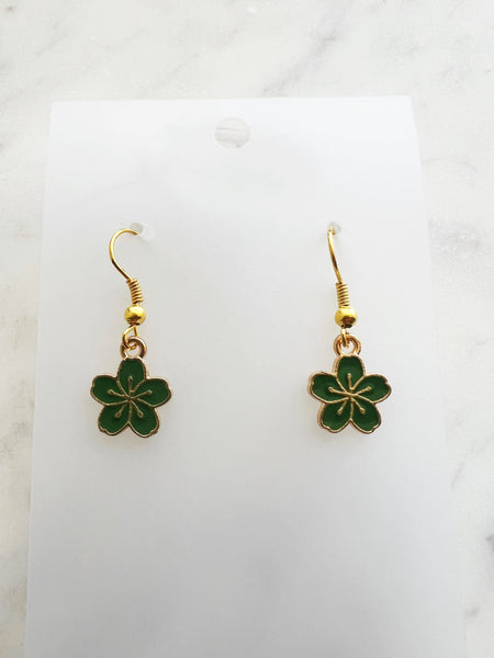 Green flower-shaped earrings on a white card with a marble background