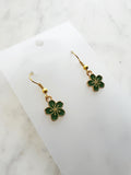 Green flower-shaped earrings on a white card with a marble background