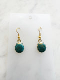 Teal earrings with gold hooks on a marble background