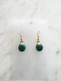Teal earrings with gold hooks on a marble background