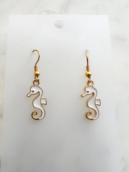 seahorse shaped earrings on a marble background