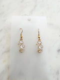 seahorse shaped earrings on a marble background
