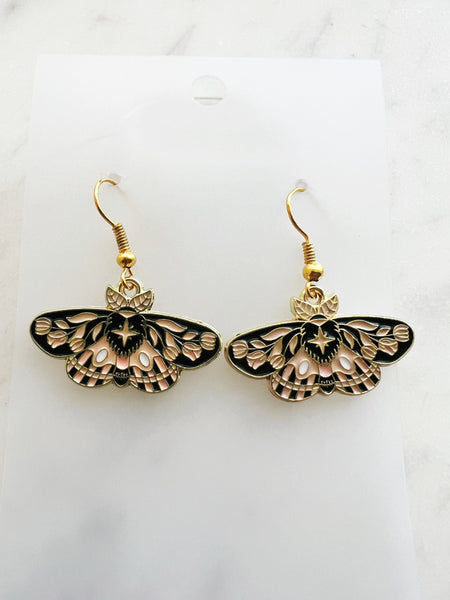 Enamel moth shaped earrings on a marble background