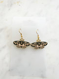 Enamel moth shaped earrings on a marble background