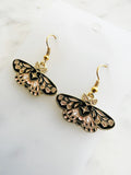 Enamel moth shaped earrings on a marble background