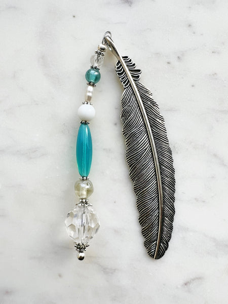 Vintage silver feather bookmark with aqua, pearl, and clear glass beads handcrafted from repurposed vintage jewellery, displayed on a marble background.