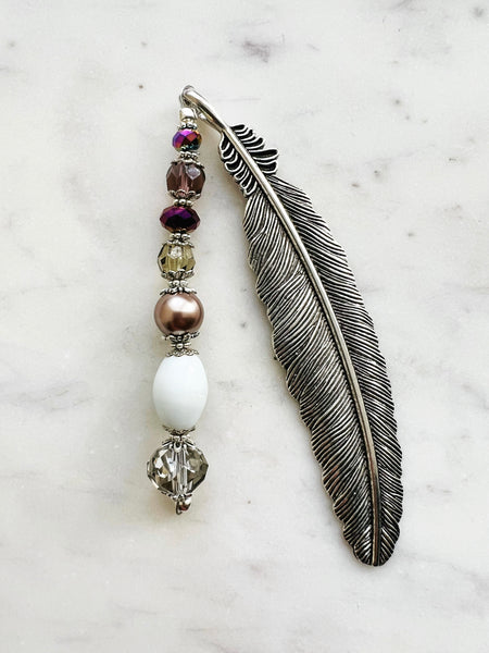 Tibetan silver feather bookmark adorned with bronze glass pearl, plum, and crystal beads handcrafted from repurposed vintage jewellery, displayed on a marble surface.