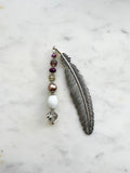 Tibetan silver feather bookmark adorned with bronze glass pearl, plum, and crystal beads handcrafted from repurposed vintage jewellery, displayed on a marble surface.