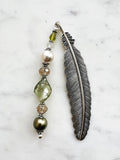Handmade feather bookmark with Tibetan silver feather and repurposed vintage beads in green, pearl, and crystal tones displayed on a marble background.