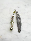 Handmade feather bookmark with Tibetan silver feather and repurposed vintage beads in green, pearl, and crystal tones displayed on a marble background.