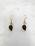 Pair of Kawaii green leaf-shaped earrings with gold hooks on a white card with marble background