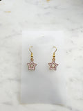 Star-shaped earrings on a white card with a marble background
