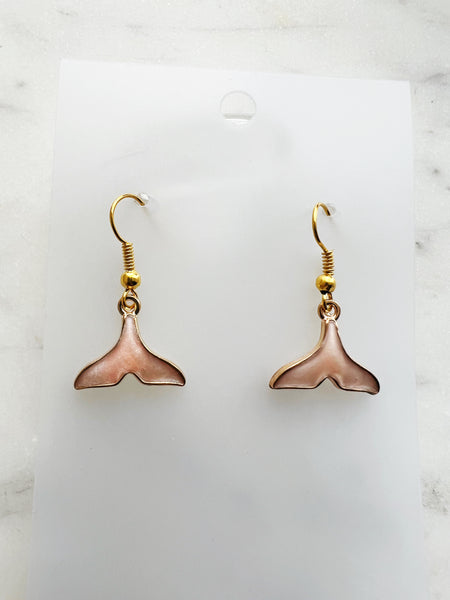 Whale tail shaped earrings on a marble background. 