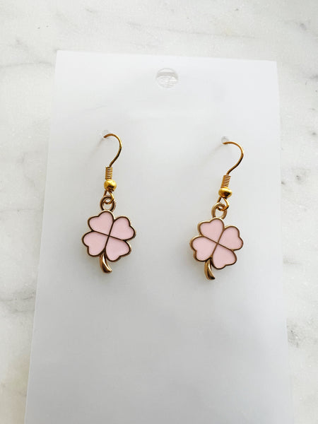 Four leaf clover shaped earrings on a marble background