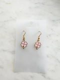 Four leaf clover shaped earrings on a marble background