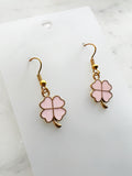 Four leaf clover shaped earrings on a marble background