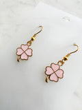 Four leaf clover shaped earrings on a marble background