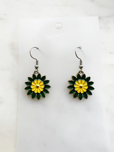 Pair of Kawaii enamel flower dangle earrings featuring green petals with a yellow centre, outlined in silver-tone metal with silver ear hooks, displayed on a marble background.