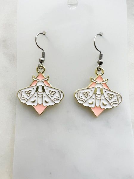 Pair of earrings with moth design on a marble  background
