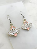 Pair of earrings with moth design on a marble  background