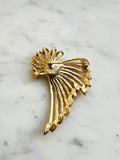 The back view of a Vintage Gold-Plated Crystal Spray Brooch with  Marquis Center on a marble background