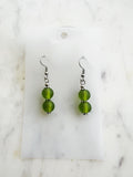 Pair of handmade frosted green vintage glass bead earrings with two stacked 10mm beads on nickel-free ear hooks, displayed on a marble backing card.