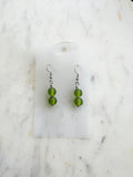 Pair of handmade frosted green vintage glass bead earrings with two stacked 10mm beads on nickel-free ear hooks, displayed on a marble backing card.