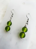 side view of a Pair of handmade frosted green vintage glass bead earrings with two stacked 10mm beads on nickel-free ear hooks, displayed on a marble backing card.