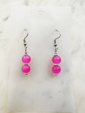 Handmade candy pink vintage glass bead dangle earrings with two fluorescent translucent beads on surgical stainless steel hooks, displayed on a white card background with Tibetan silver spacers