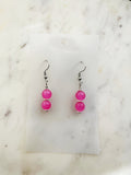 Handmade candy pink vintage glass bead dangle earrings with two fluorescent translucent beads on surgical stainless steel hooks, displayed on a white card background with Tibetan silver spacers