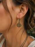 Close-up of a woman's ear wearing a dark bronze Celtic knot dangle earring.