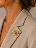 A close-up of a model wearing a gold turtle-shaped lapel pin on a beige blazer.
